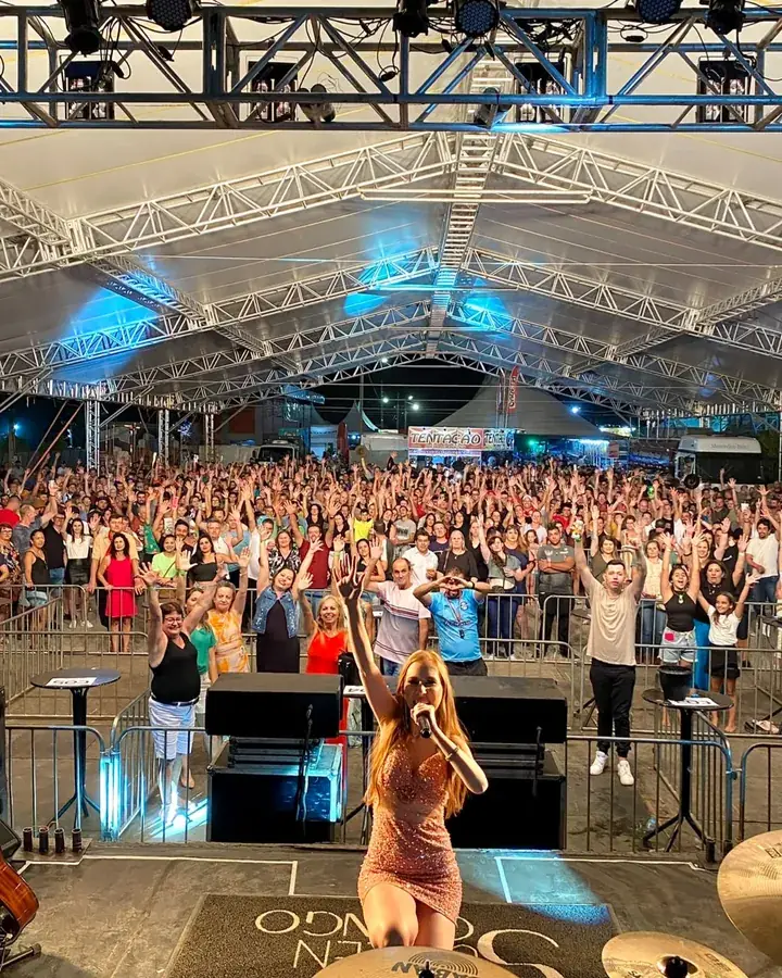 Rafaela Martins no palco, de frente para o público, numa tenda cheia